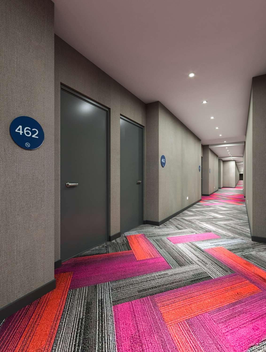 A hotel corridor with a carpeted floor, doors, and a number sign.