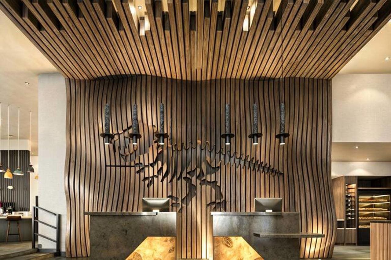 Un área de recepción con diseño de pared de madera, un pilar central e iluminación colgante.