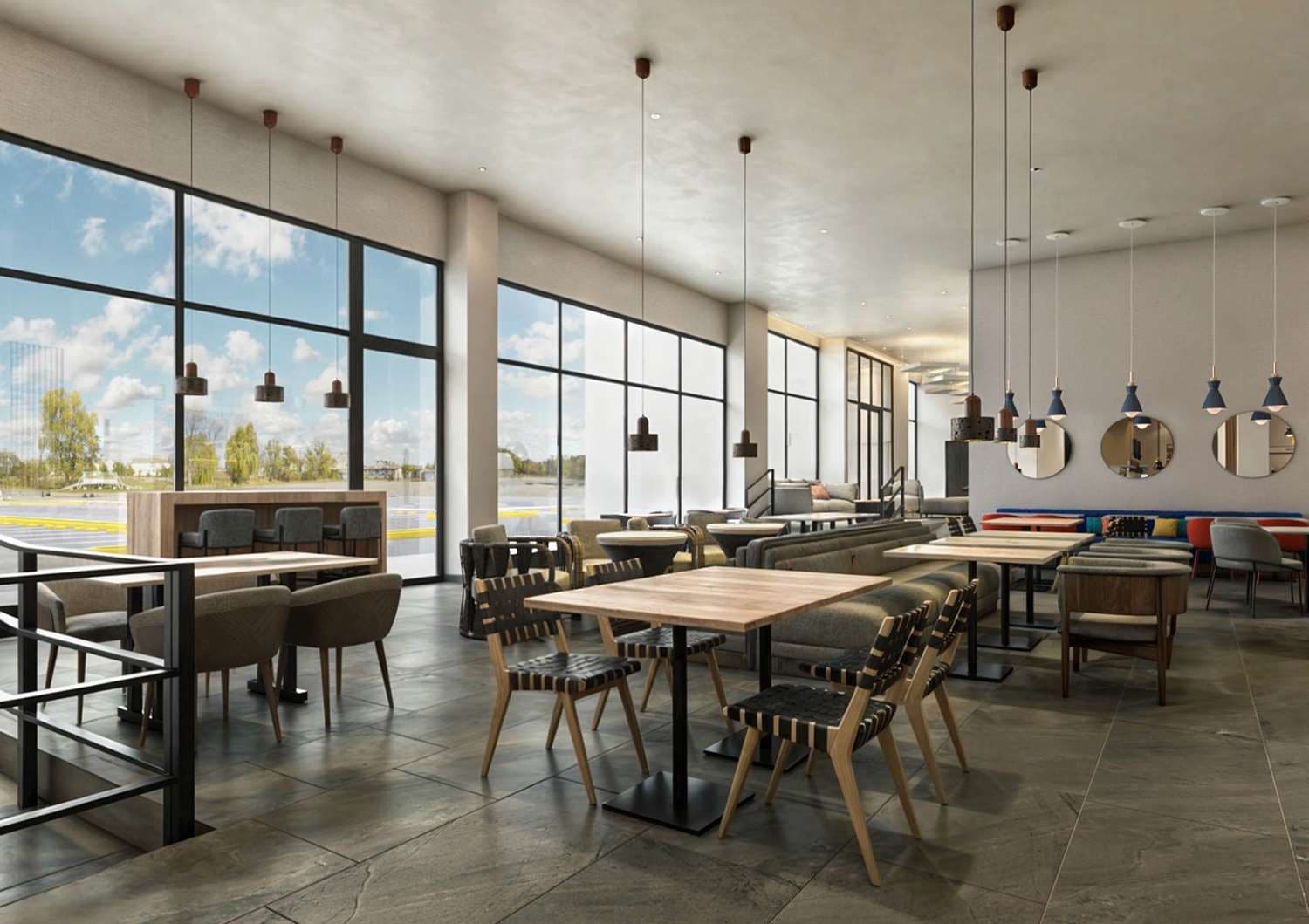 A spacious indoor area with large windows, multiple seating arrangements, and hanging pendant lights.