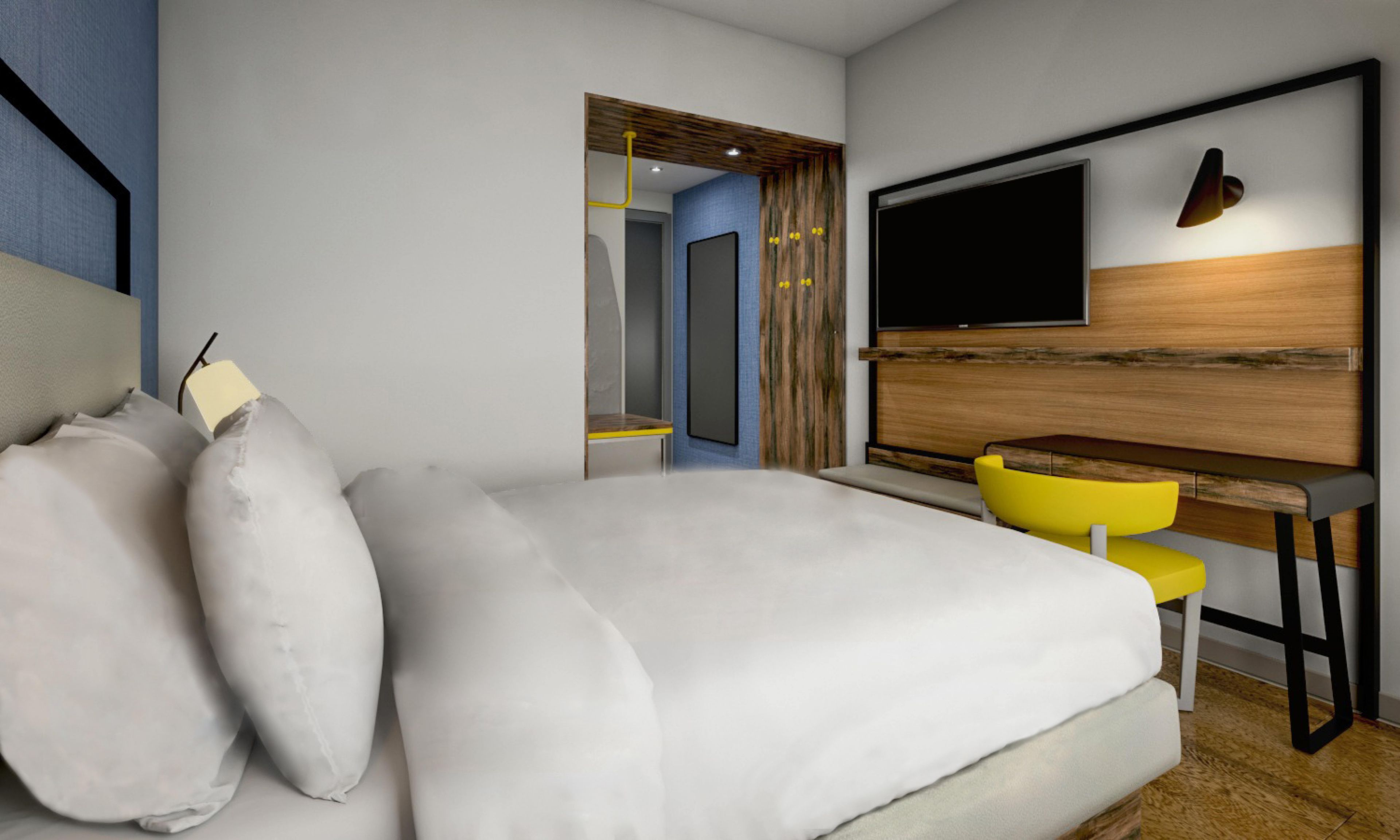 Habitación de hotel moderna con una cama grande, un escritorio, una silla, un televisor de pantalla plana y un espejo.