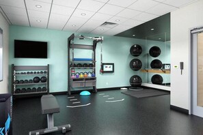 A gym with exercise equipment, a wall-mounted TV, and a mirror. - Tru by Hilton Saltillo (Saltillo)