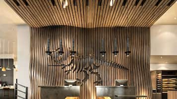 Un área de recepción con diseño moderno, que presenta una pared de madera con listones verticales y una escultura abstracta en el centro.