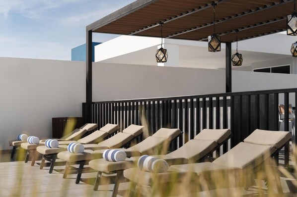 A rooftop lounge area with sun loungers and hanging lanterns. - Tru by Hilton Saltillo (Saltillo)