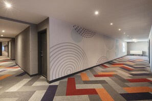 Passadís d'hotel amb un mosaic estampat, una porta i una paret amb dibuixos circulars.