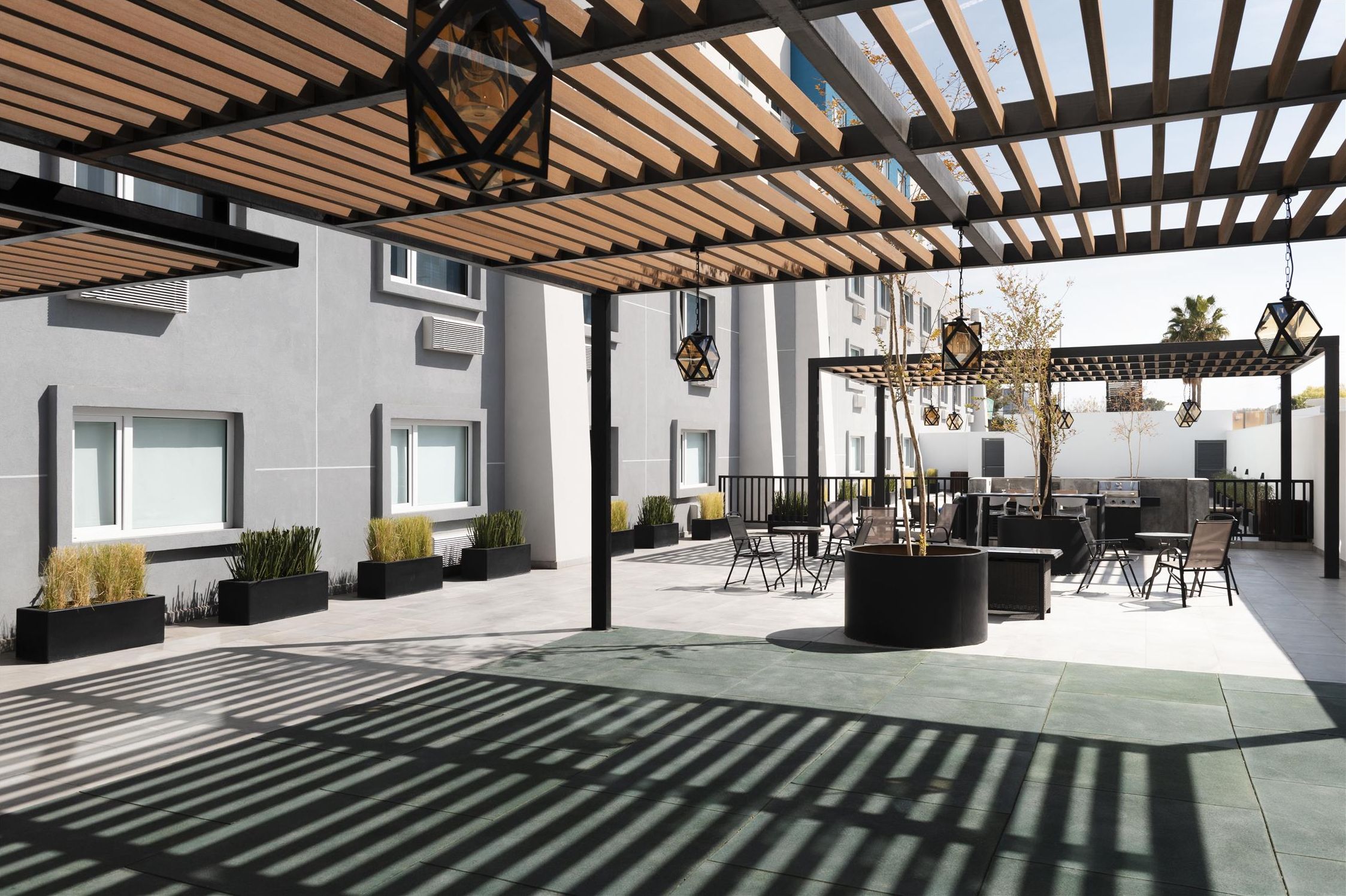 Un patio al aire libre con una pérgola, asientos y jardineras.