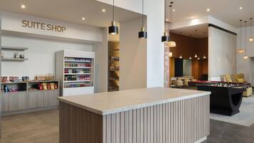 Un moderno vestíbulo de hotel con mesa de fútbol, minibar y un letrero que dice 'SUITE SHOP'.