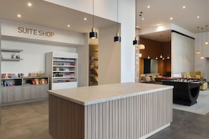 A modern hotel lobby with a foosball table, a minibar, and a 'SUITE SHOP' sign. - Tru by Hilton Saltillo (Saltillo)