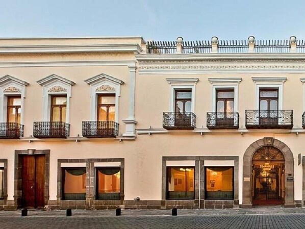 A building with multiple windows, balconies, and an entrance with a decorative arch. - Palacio San Leonardo (Puebla)