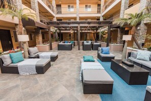 Ein großzügiger Außenbereich mit Loungemöbeln, darunter Sofas und Sessel, die um einen zentralen offenen Platz angeordnet sind.