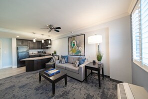 A modern living room with a sofa, coffee table, and a kitchen in the background. - Manhattan Beach Hotel (Manhattan Beach)