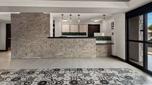 A modern interior with a stone accent wall, a patterned floor, and pendant lighting. - Manhattan Beach Hotel (Manhattan Beach)