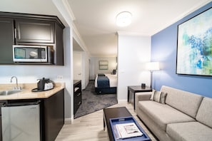Ein modernes Hotelzimmer mit Küchenzeile, einer Couch, einem Couchtisch und einem Bild an der Wand.