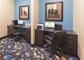 Une chambre d’hôtel avec deux bureaux, des chaises, une moquette à motifs circulaires et deux tableaux encadrés accrochés au mur.