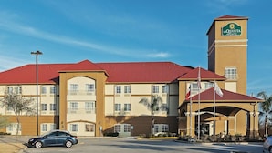 A La Quinta Inn & Suites hotel with a red roof, beige walls, and a prominent tower. - Houston Hobby Airport (Houston)