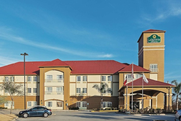 Un hôtel La Quinta Inn & Suites avec un toit rouge, des murs de couleur beige et une tour imposante.