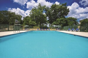 Una piscina rectangular con una escalera de metal en un lateral, rodeada por una cerca verde.