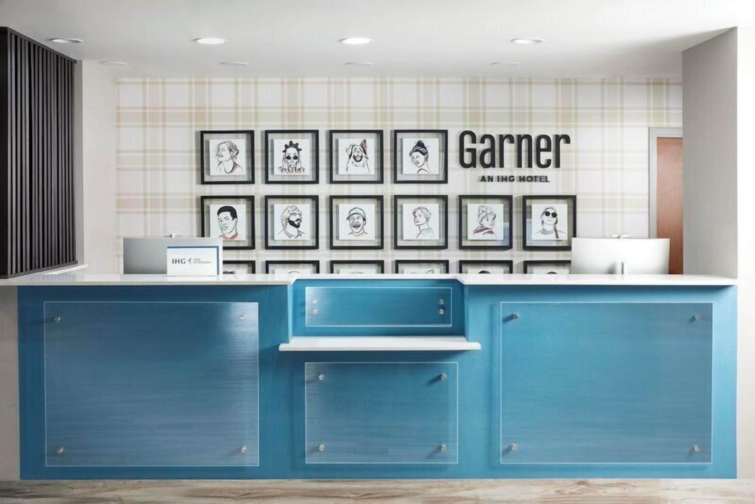 Un mostrador de recepción de hotel con retratos enmarcados en la pared, una barra azul y un cartel que dice 'Garner AN ING HOTEL'.
