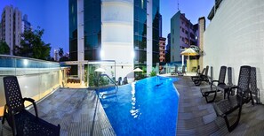 A rooftop pool with lounge chairs, a glass balustrade, and modern buildings in the background. - Grand International Hotel (Panama City)