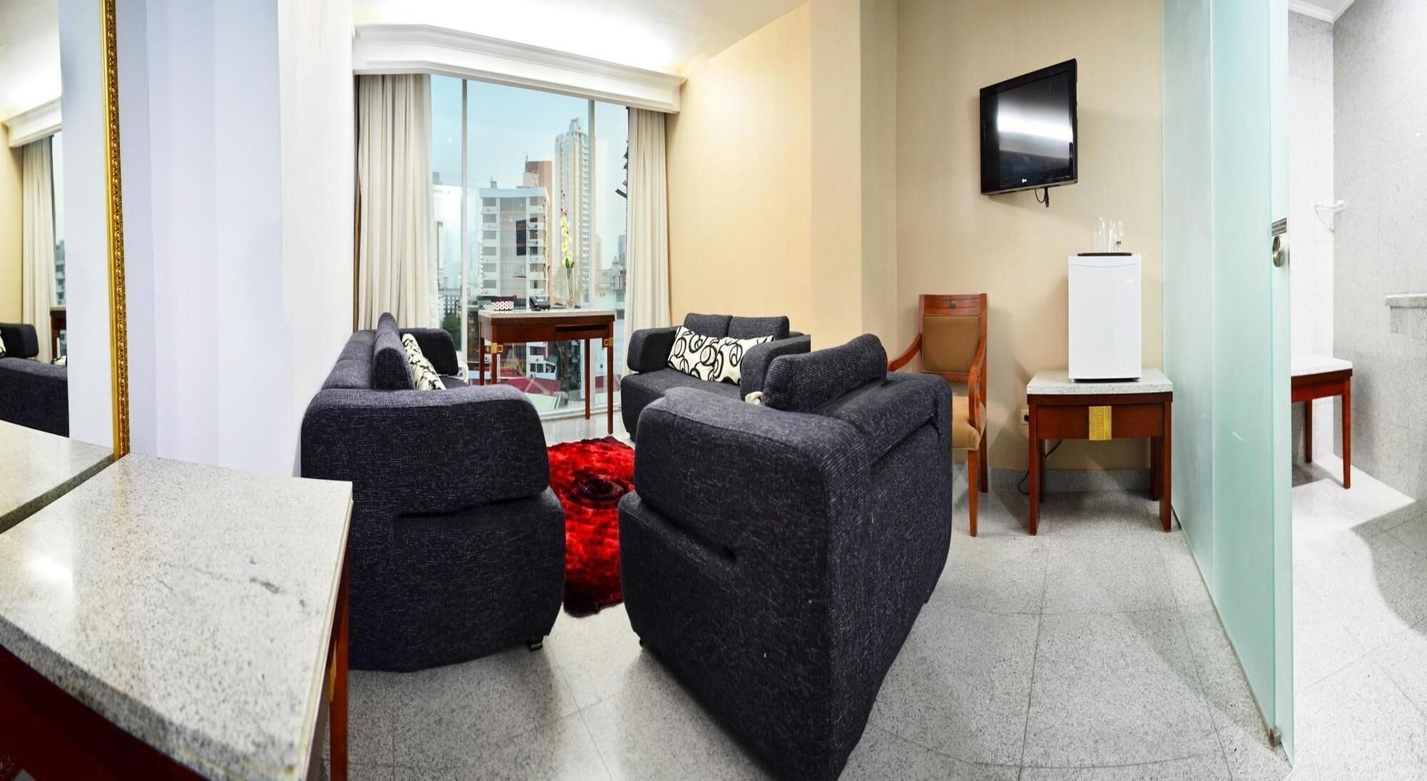 Habitación de hotel moderna con zona de estar, televisor de pantalla plana y vistas a la ciudad.