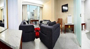 Habitación de hotel moderna con zona de estar, televisor de pantalla plana y vistas a la ciudad.