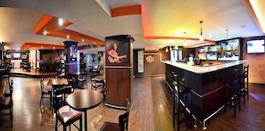 A bar area with a counter, stools, and a large screen. - Grand International Hotel (Panama City)