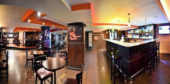 Zona de bar con mostrador, taburetes y una pantalla grande.
