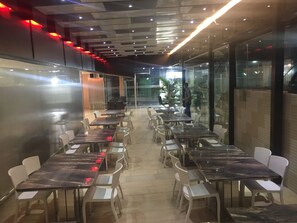 Un vaste espace de restauration intĂ©rieur, dotĂ© de nombreuses tables et chaises, dâun design de plafond moderne et de grandes fenĂȘtres laissant entrer la lumiĂšre naturelle.