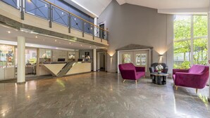 A spacious lobby with a reception desk, seating area, and a view of the outdoors. - Hotel Schmoeker-hof (Norderstedt)