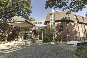 A hotel with a brick facade, a covered entrance, and satellite dishes on the roof. - Hotel Schmoeker-hof (Norderstedt)