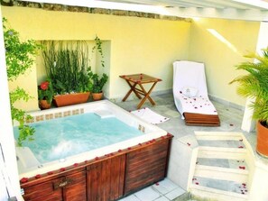 A spa area with a hot tub, wooden deck, and potted plants. - Dona Urraca Hotel and Spa (Querétaro)