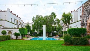 A courtyard with a swimming pool, surrounded by white buildings with stone accents, and string lights overhead. - Dona Urraca Hotel and Spa (Querétaro)