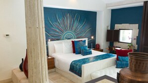 A bedroom with a large bed, a headboard with a mural, a nightstand, and a bedside table.