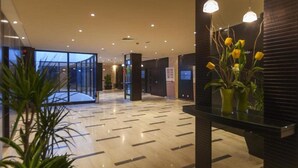 Un moderno vestíbulo de hotel con un separador de vidrio, una recepción y una planta en maceta.