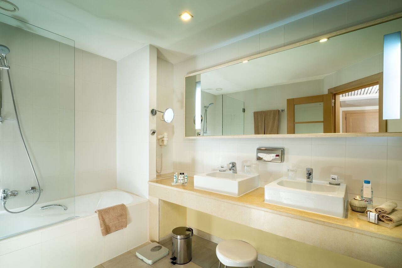 A modern bathroom with a bathtub, two sinks, a large mirror, and a shower.