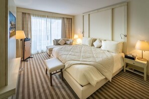 Una habitación de hotel con una cama grande, mesitas de noche, un banco y un escritorio.