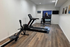 Ein Heimfitnessraum mit Laufband, Ergometer und Rudergerät.