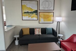 Un salon moderne avec un canapé, un fauteuil rouge, une table basse et un lampadaire.
