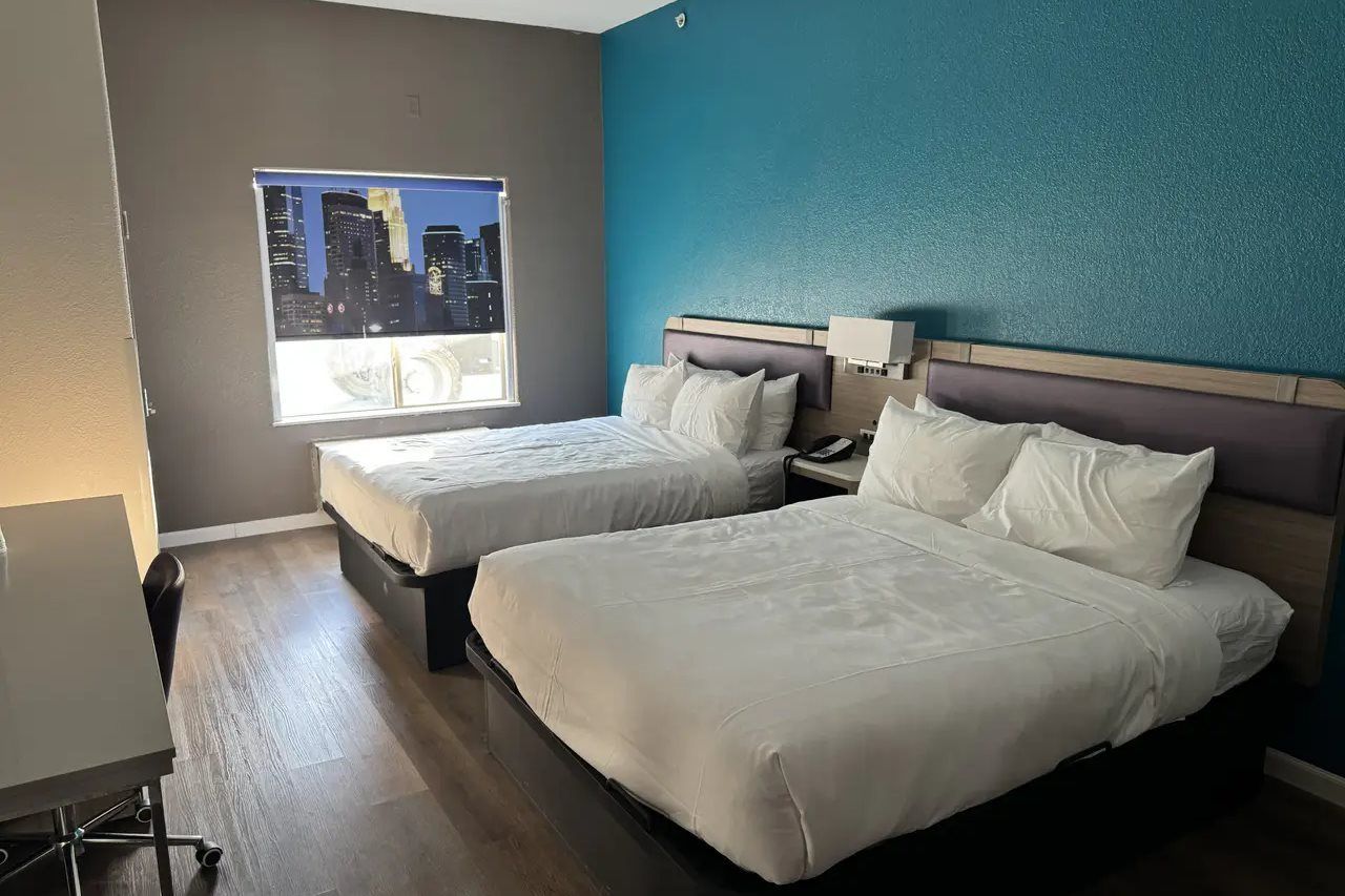 Une chambre d’hôtel avec deux lits, un bureau et une fenêtre donnant sur la ville.