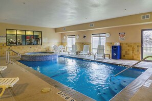 Una piscina interior con un jacuzzi, sillas de descanso y un letrero de salvavidas.