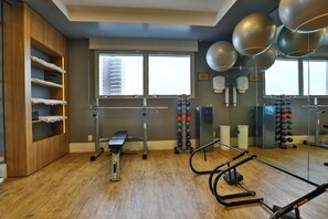 A gym with exercise equipment, a bench, and a mirror. - Roomo Santos Residencial (Santos)