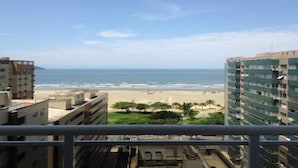 Vista de una playa desde un balcón, con edificios al frente.