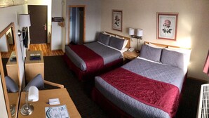 Une chambre d’hôtel avec deux lits, un bureau, une chaise, un miroir et une porte.