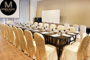 A conference room with a long table, chairs with white covers, water bottles, and a whiteboard. - Mtree Hotel (Puchong)