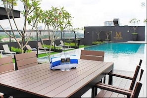 Área de piscina no terraço com espreguiçadeiras, uma mesa com garrafas de água e uma placa indicando 'Mtree Hotel'.