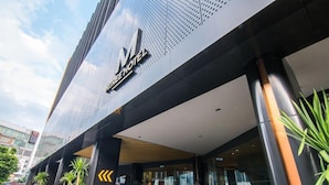Una entrada de hotel moderna con un logotipo destacado, un vestíbulo cubierto y un fachada de vidrio.