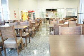A dining area with wooden tables and chairs, a fire extinguisher, and vending machines. - Samba Foz do Iguassu (Foz do Iguaçu)