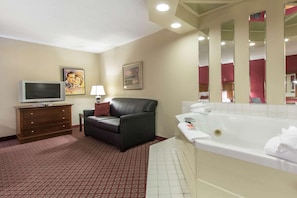 A hotel room with a television, a sofa, a bathtub, and a mirror. - Econo Lodge Inn and Suites Joplin MO (Joplin)