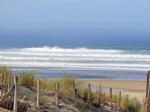 A beach with waves, a sandy shore, and a wooden fence. - Clairière aux Chevreuils by Interhome (Moliets)