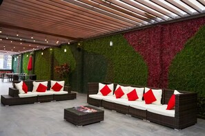 A modern lounge area with a sectional sofa and a coffee table, surrounded by a green and red textured wall. - Comfort Inn Puebla Centro Historico (Puebla)