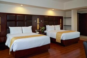 A hotel room with two beds, a wooden headboard, a bedside table with a lamp, and a wall-mounted shelf. - Comfort Inn Puebla Centro Historico (Puebla)